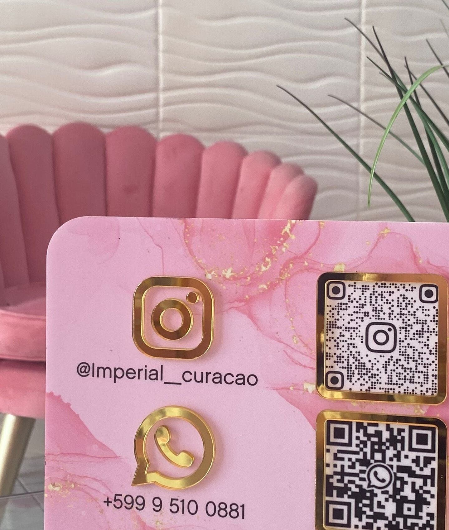 Stylish contact card at Imperial Curacao in Willemstad, Curaçao, CW beside pink velvet chair and green plant.