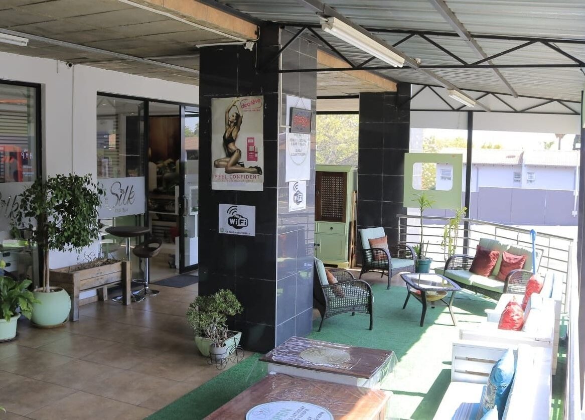 Charming outdoor lounge at Silk Day Spa, Sandton, Gauteng, ZA with cozy seating and lush plants.