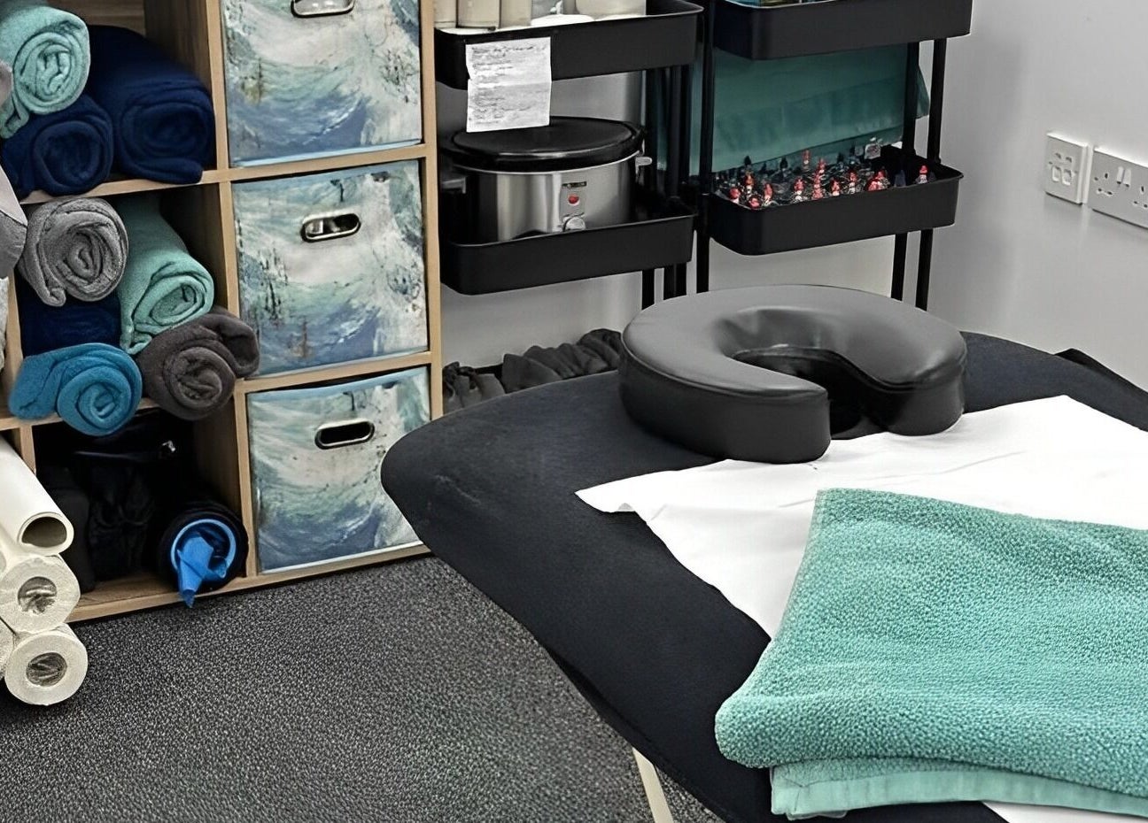 Massage room setup at The Recovery Room, Suton, England, GB with neatly arranged towels and massage table.