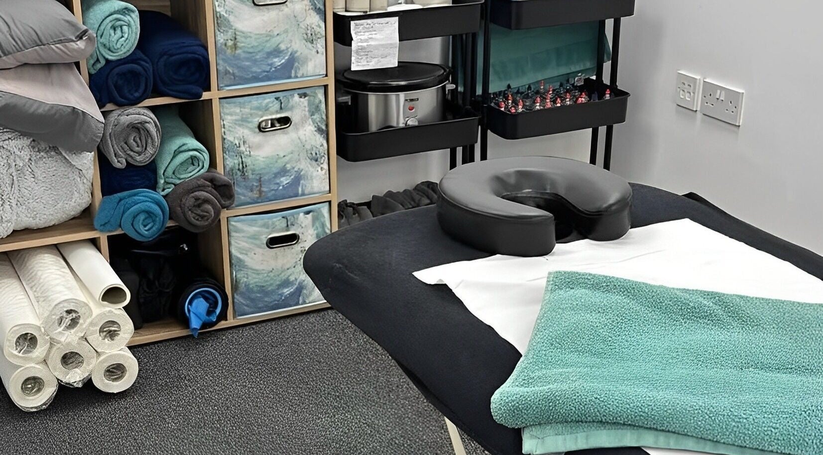 Massage room setup at The Recovery Room, Suton, England, GB with neatly arranged towels and massage table.