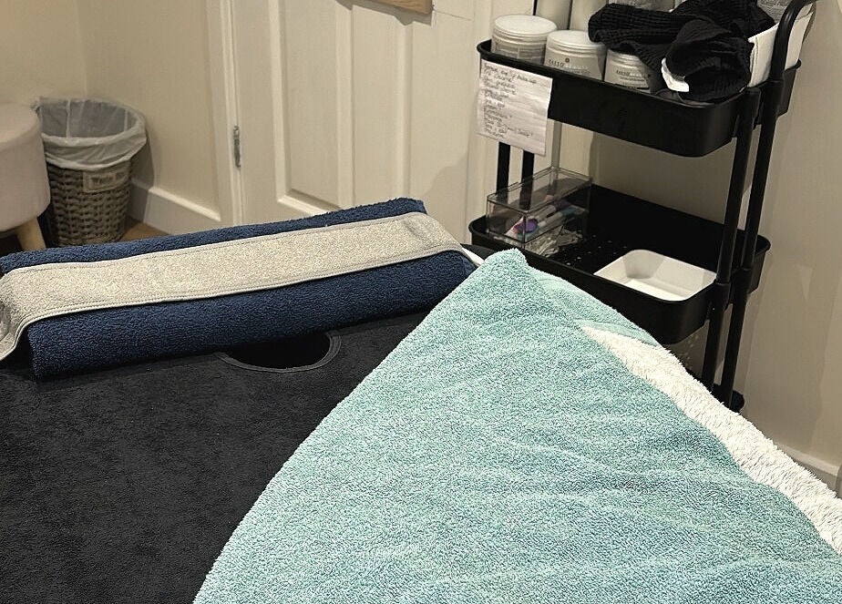Cozy treatment room at The Recovery Room, Suton, England, GB with a massage table and soft towels.