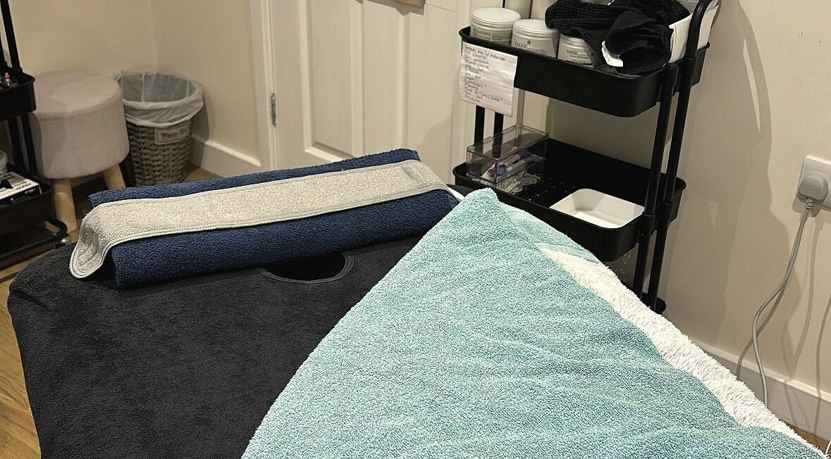 Cozy treatment room at The Recovery Room, Suton, England, GB with a massage table and soft towels.