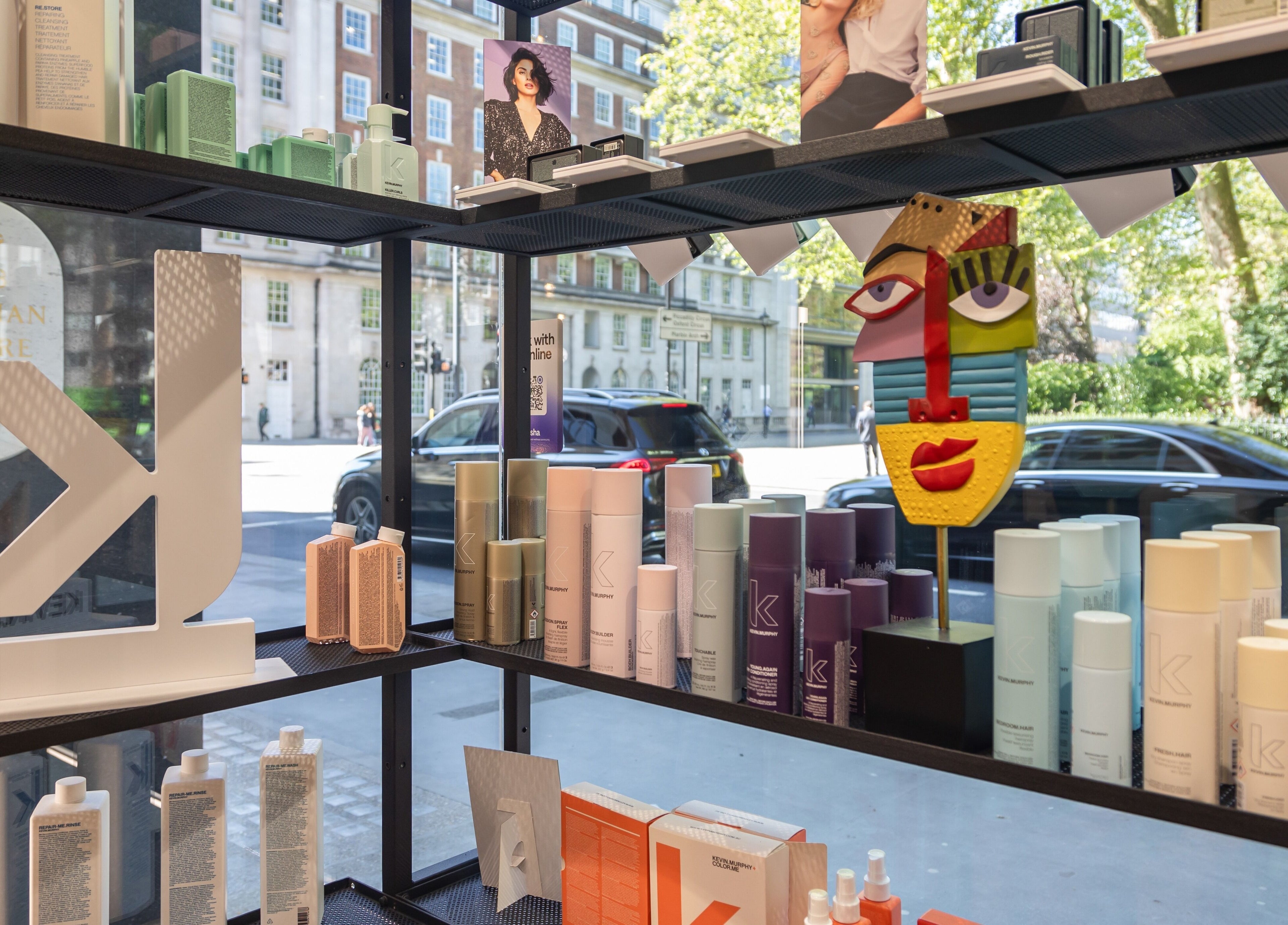 Colorful haircare products on shelves at Shadi, London, England, GB, showcasing vibrant packaging and street view.