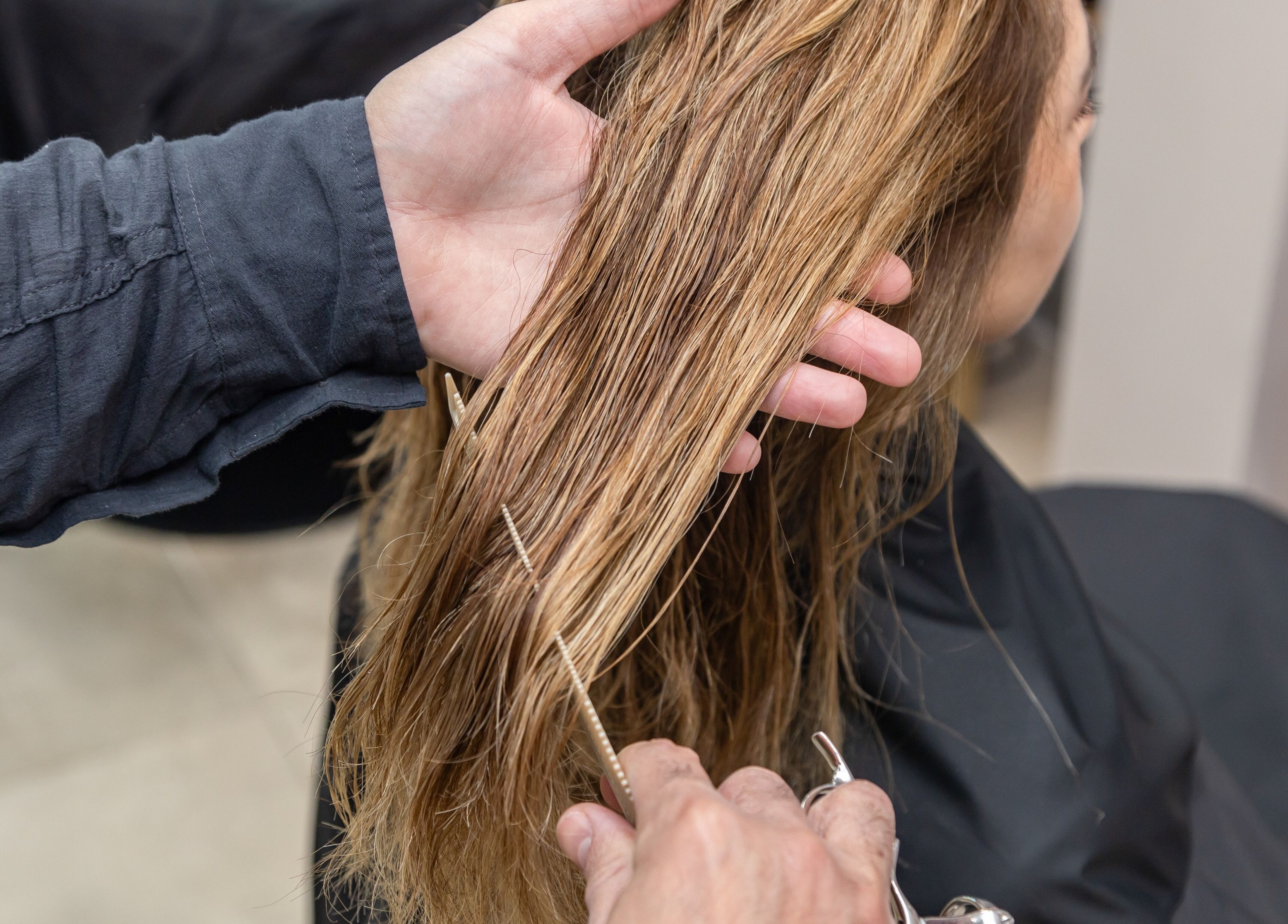 Haircut in progress at Shadi, London, England, GB. Stylist trims hair with precision.