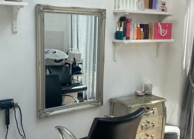 Chic salon interior at Andria Loizou Hair, London, England, GB featuring a mirror, styling chair, and products.