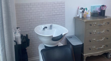 Wash station at Andria Loizou Hair, London, England, GB featuring a white basin and products.