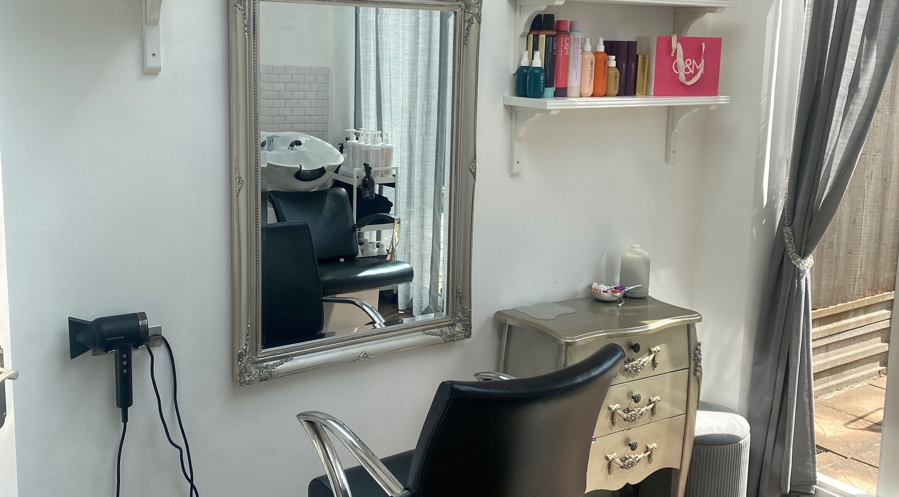 Elegant salon station at Andria Loizou Hair, London, England, GB, featuring a mirror, chair, and hair products.