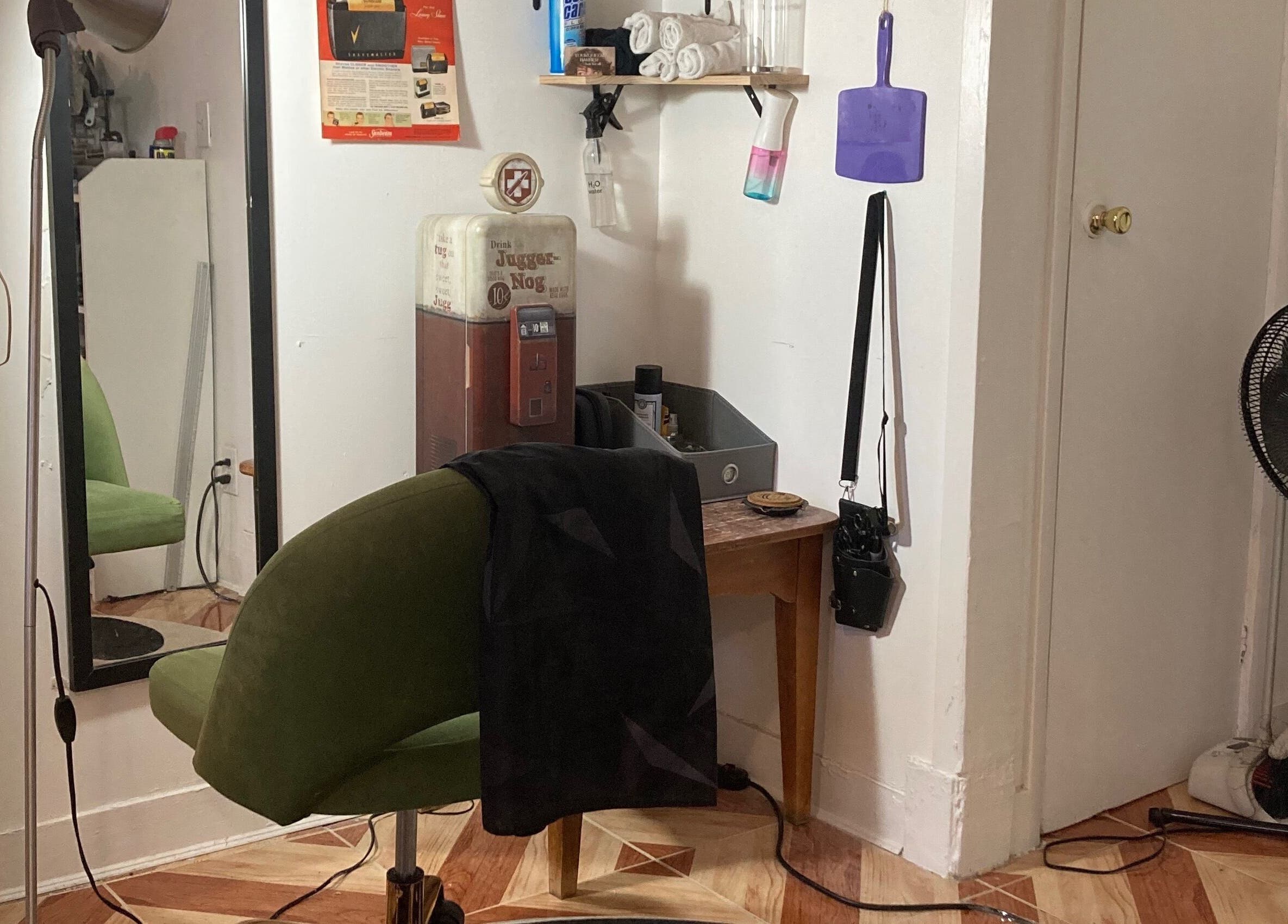 Cozy barber corner at Your Queer Barber, New York, New York, US with green chair and retro decor.