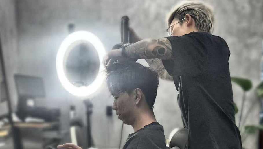 Stylist at 9t3 Barber Studio in Auckland, Auckland, NZ, expertly trims a client's hair under modern lighting.