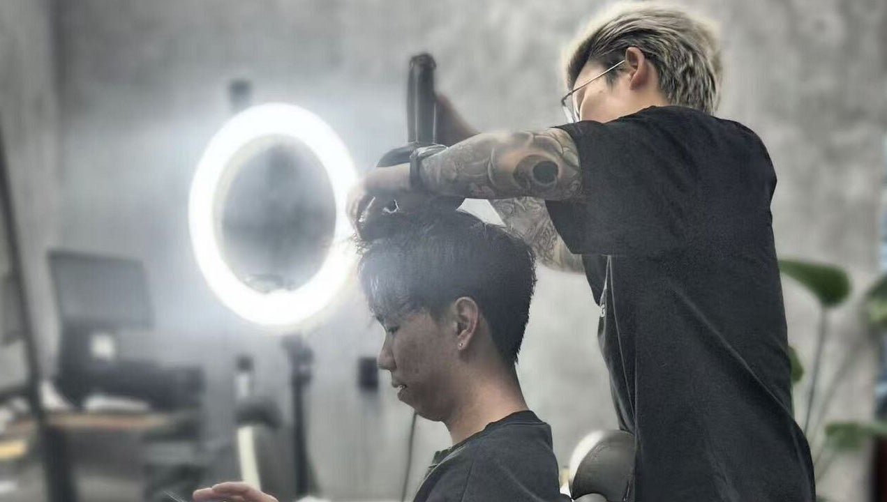 Stylist at 9t3 Barber Studio in Auckland, Auckland, NZ, expertly trims a client's hair under modern lighting.