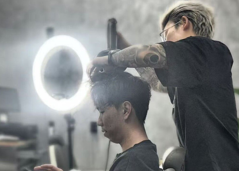 Stylist at 9t3 Barber Studio in Auckland, Auckland, NZ, expertly trims a client's hair under modern lighting.