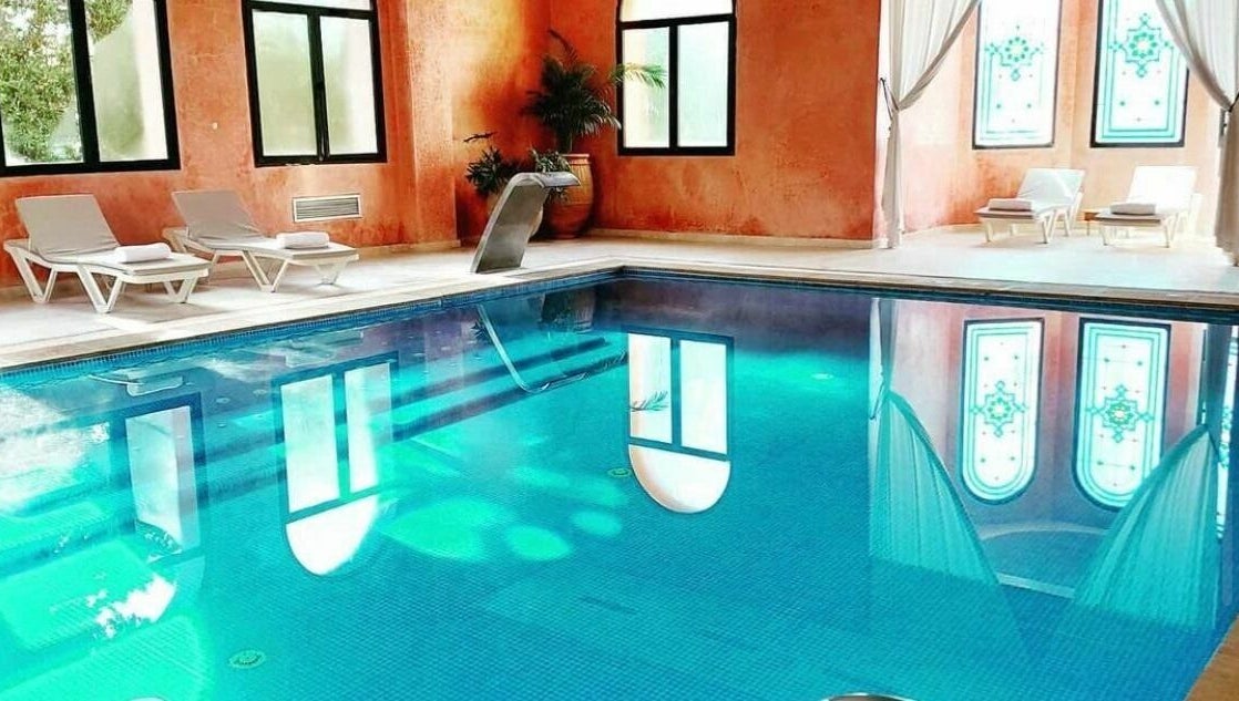 Piscine intérieure élégante à Wud Spa, El Bour, Marrakesh-safi, MA avec chaises longues et superbe éclairage.