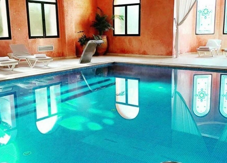 Piscine intérieure élégante à Wud Spa, El Bour, Marrakesh-safi, MA avec chaises longues et superbe éclairage.