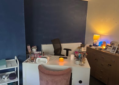 Beautylicious cozy treatment space in Poole, England, GB with vibrant blue walls and a well-organized desk.