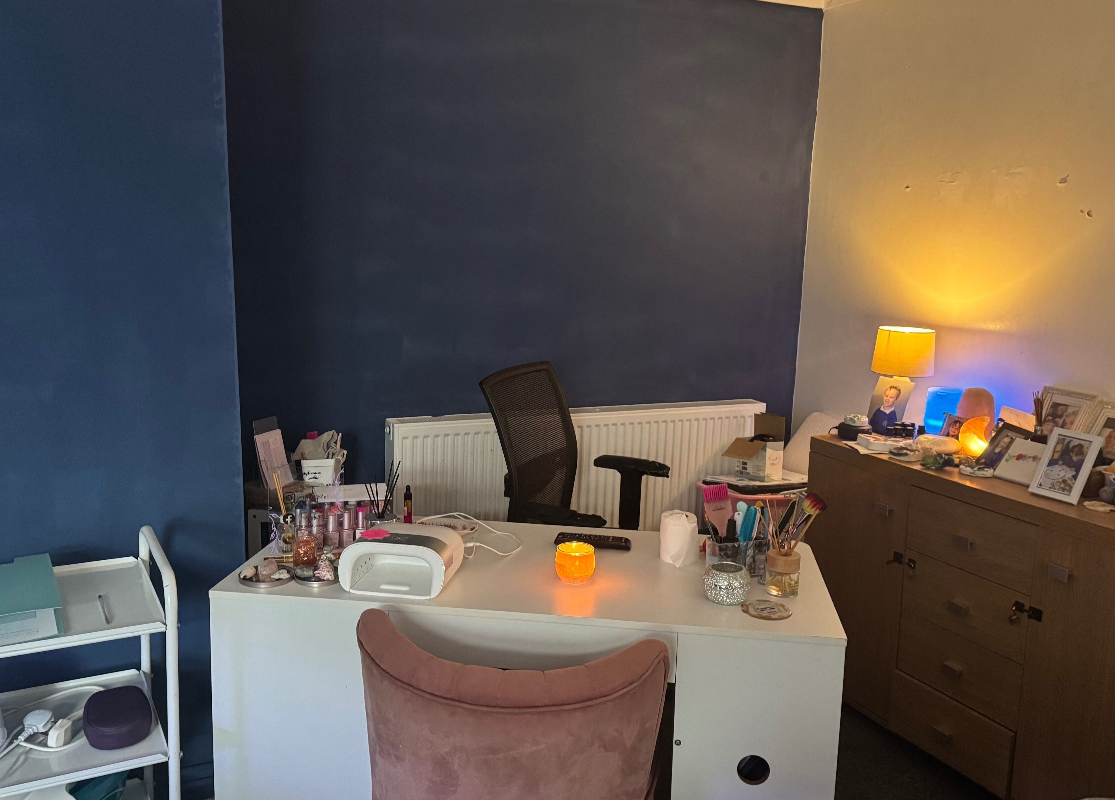 Beautylicious cozy treatment space in Poole, England, GB with vibrant blue walls and a well-organized desk.