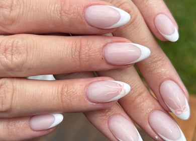 Elegant French manicure at Nails by Shanté, Pretoria, Gauteng, ZA showcasing white tips and subtle bow design.