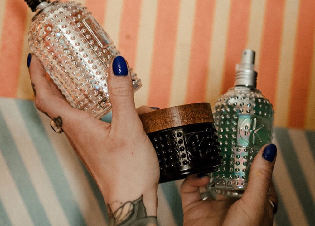 Colorful glass bottles held by tattooed hands at Third Hand Salon, Rock Island, Illinois, US.
