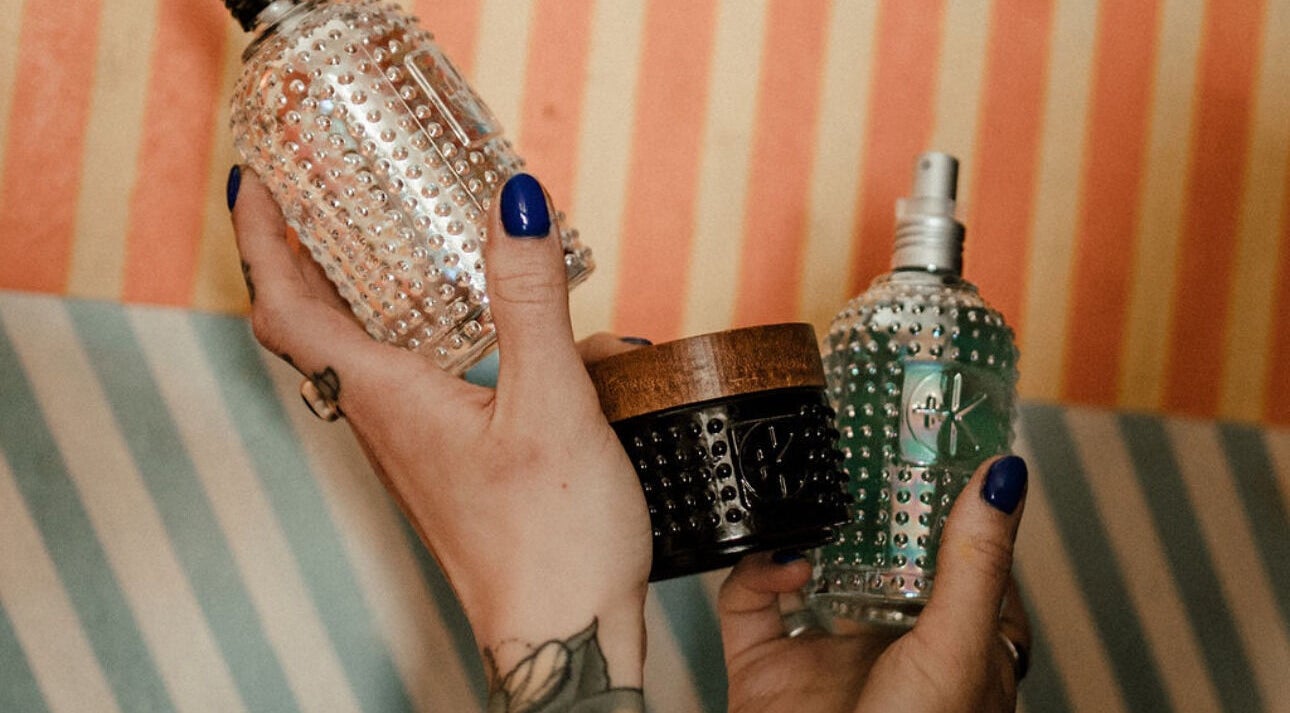 Colorful glass bottles held by tattooed hands at Third Hand Salon, Rock Island, Illinois, US.
