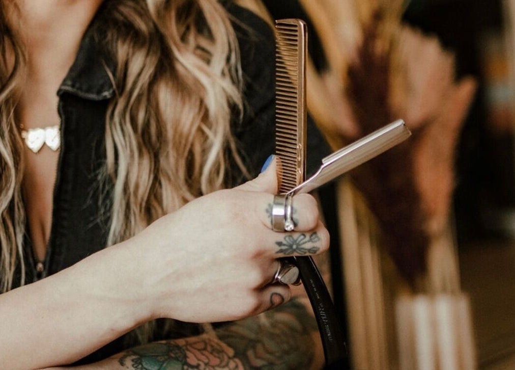 Stylist holding hair tools at Third Hand Salon in Rock Island, Illinois, US, showcasing expertise and style.