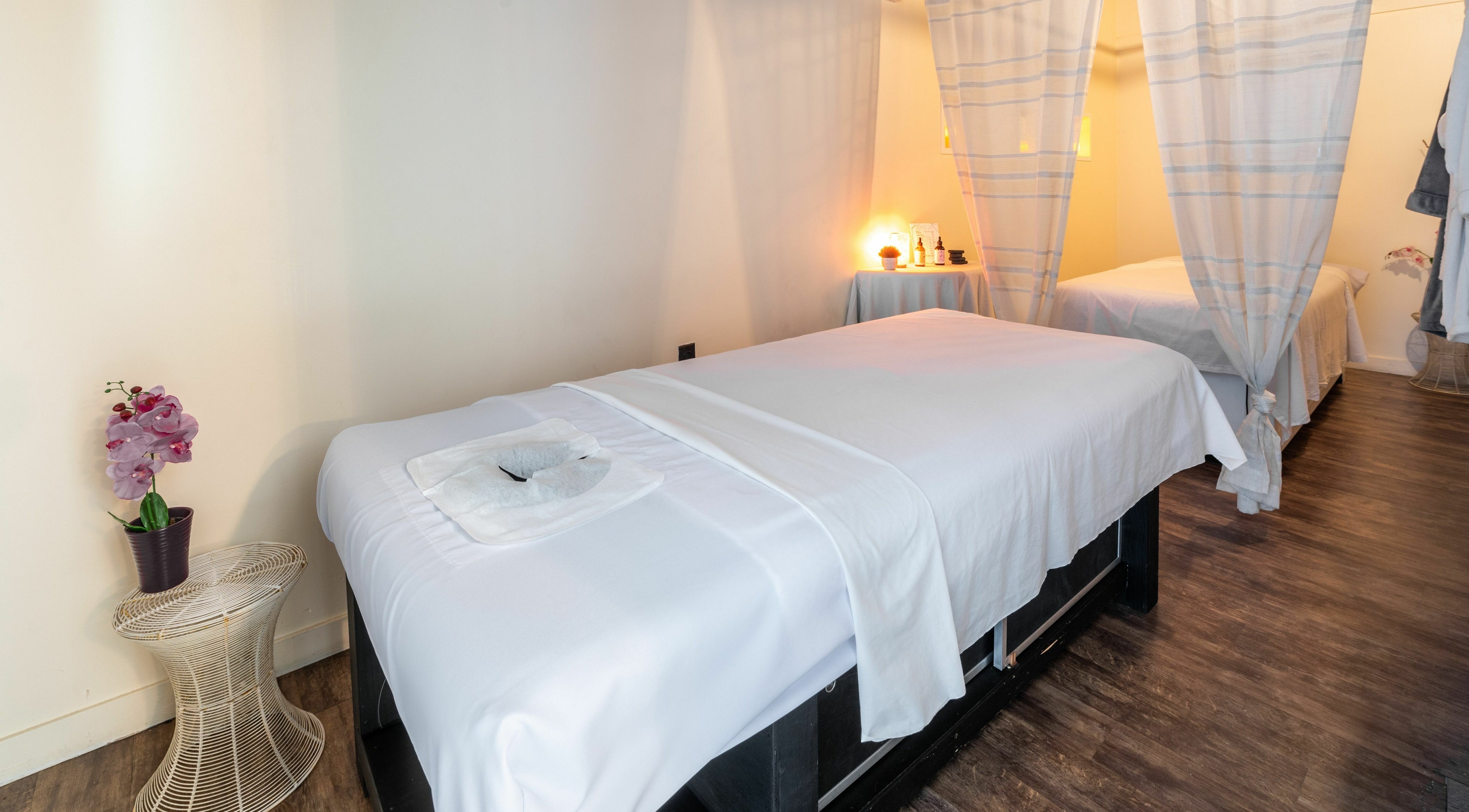 Peaceful massage room at Spa De' La in Los Angeles, California, US with soft lighting and white linens.