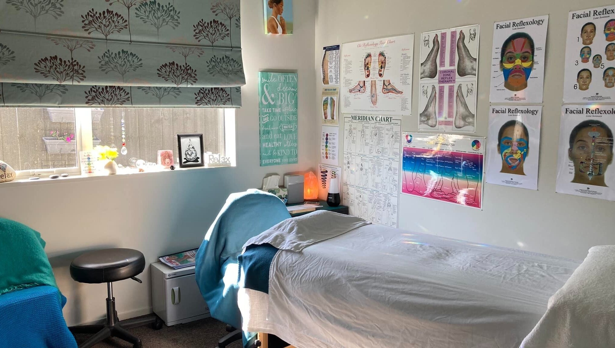 Relaxing treatment room at Cath Relaxology in Kaiapoi, Canterbury, NZ with posters and a massage bed.