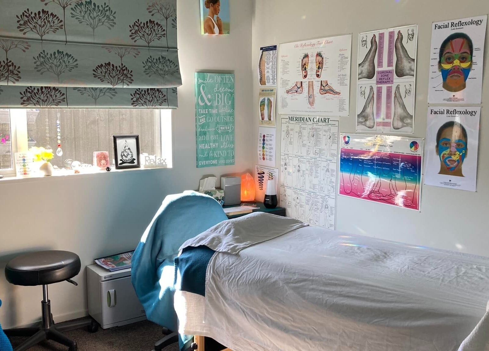 Relaxing treatment room at Cath Relaxology in Kaiapoi, Canterbury, NZ with posters and a massage bed.