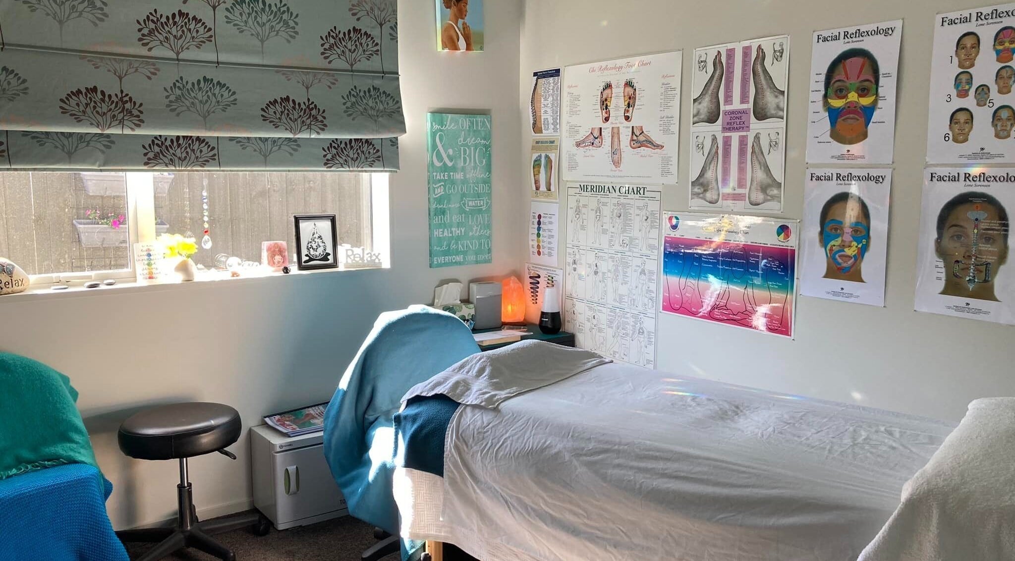Relaxing treatment room at Cath Relaxology in Kaiapoi, Canterbury, NZ with posters and a massage bed.