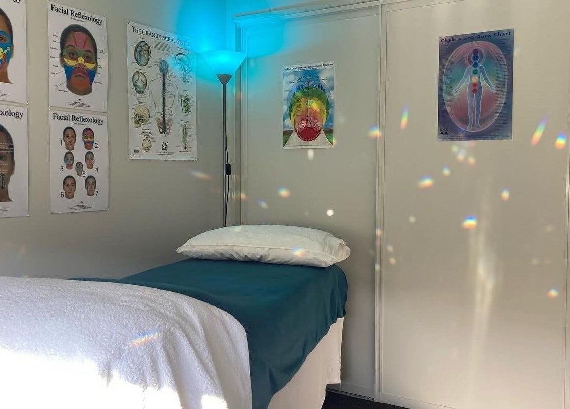 Calm therapy room at Cath Relaxology, Kaiapoi, Canterbury, NZ, featuring a treatment bed and educational diagrams.