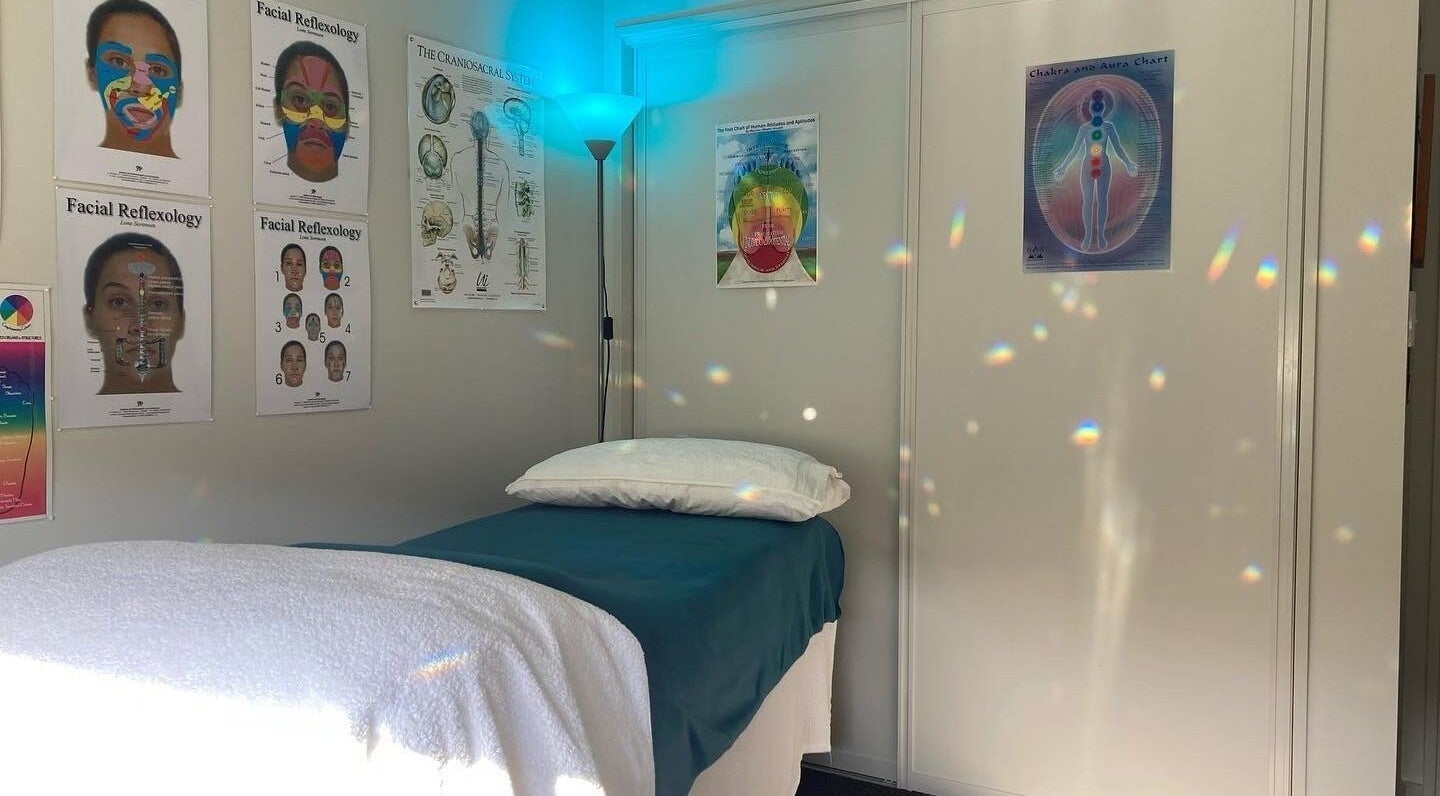 Calm therapy room at Cath Relaxology, Kaiapoi, Canterbury, NZ, featuring a treatment bed and educational diagrams.