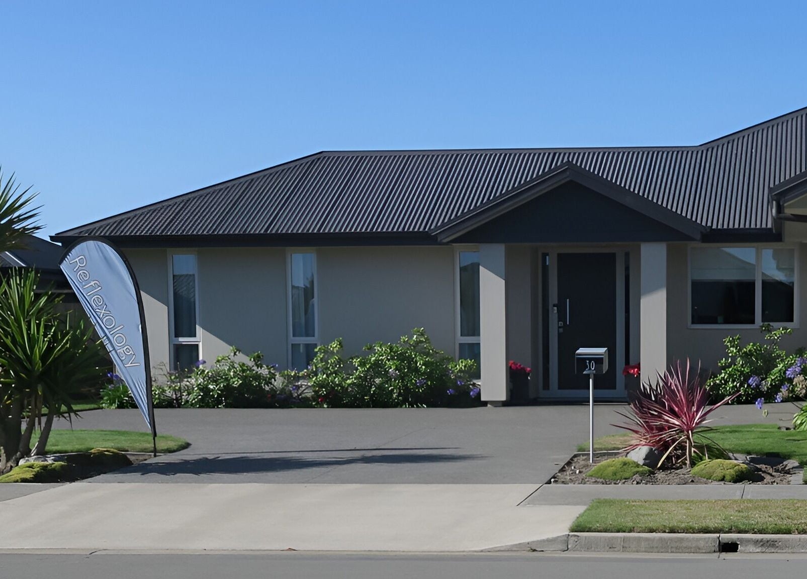 Exterior view of Cath Relaxology at Kaiapoi, Canterbury, NZ, showcasing lush greenery and a welcoming entrance.