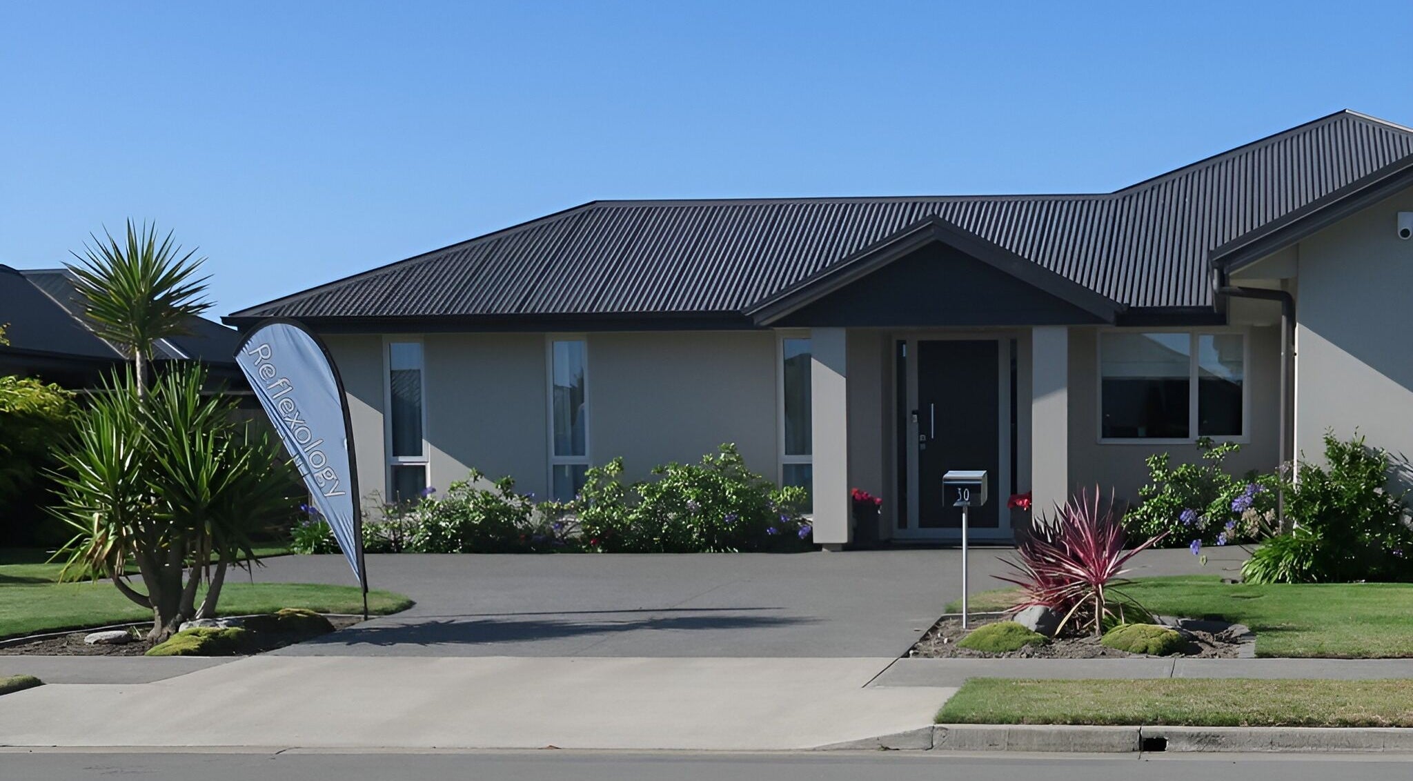 Exterior view of Cath Relaxology at Kaiapoi, Canterbury, NZ, showcasing lush greenery and a welcoming entrance.