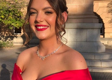 Smiling woman in red dress outside Beachbums Tanning & Hair Bribie, Bongaree, Queensland, AU.