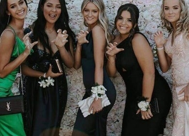 Guests dressed elegantly at Beachbums Tanning & Hair Bribie, Bongaree, Queensland, AU in front of floral wall.