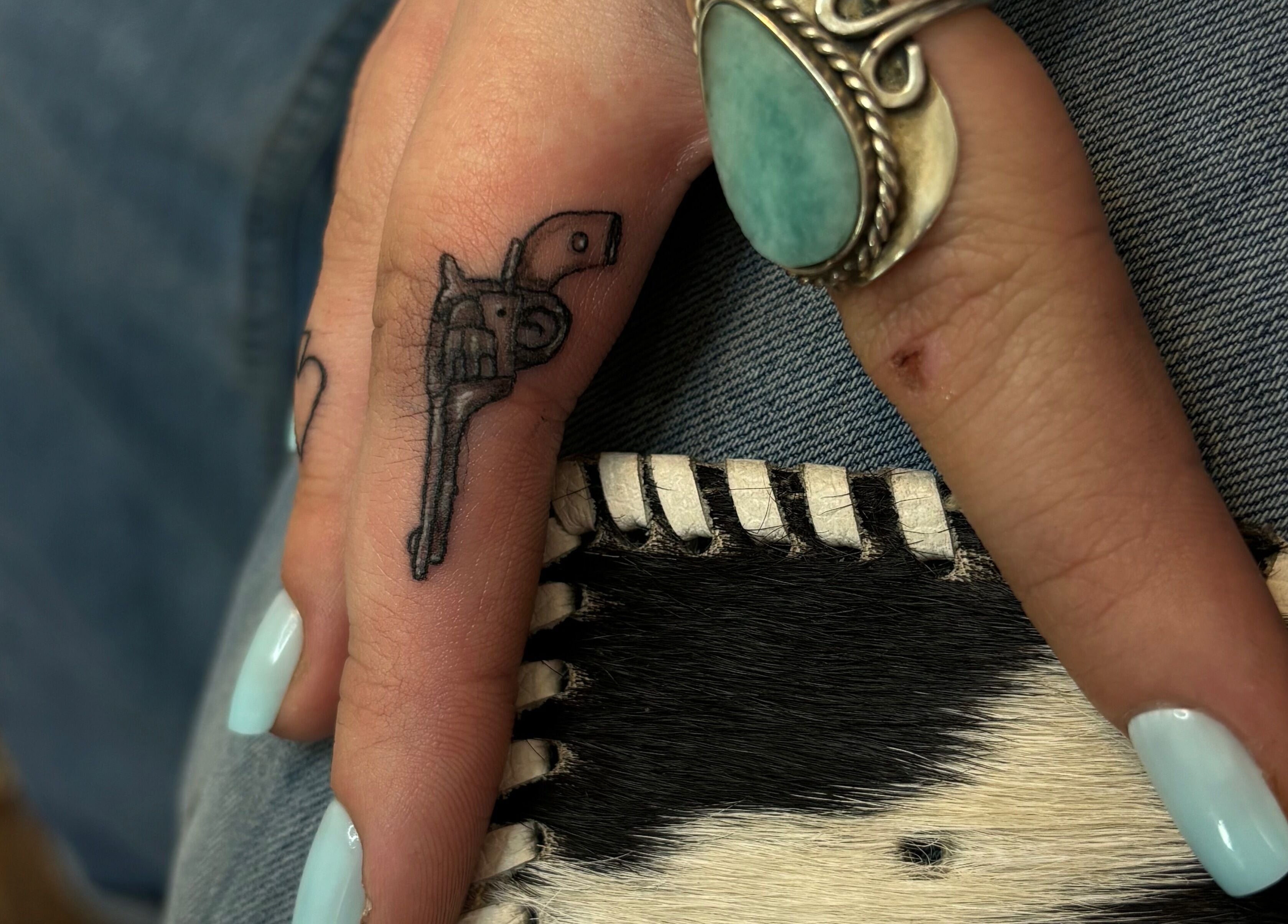 Detailed finger tattoo with turquoise ring at Longhorn Beauty Academy, Post Falls, Idaho, US.