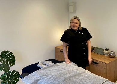 Therapist at The Retreat Room in Southend-on-sea, England, GB beside massage bed.
