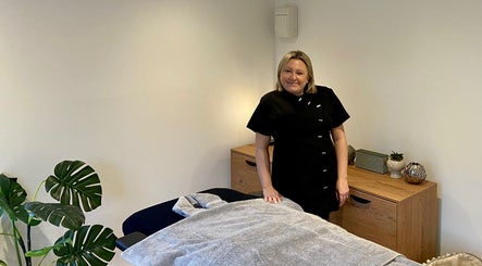 Therapist at The Retreat Room in Southend-on-sea, England, GB beside massage bed.