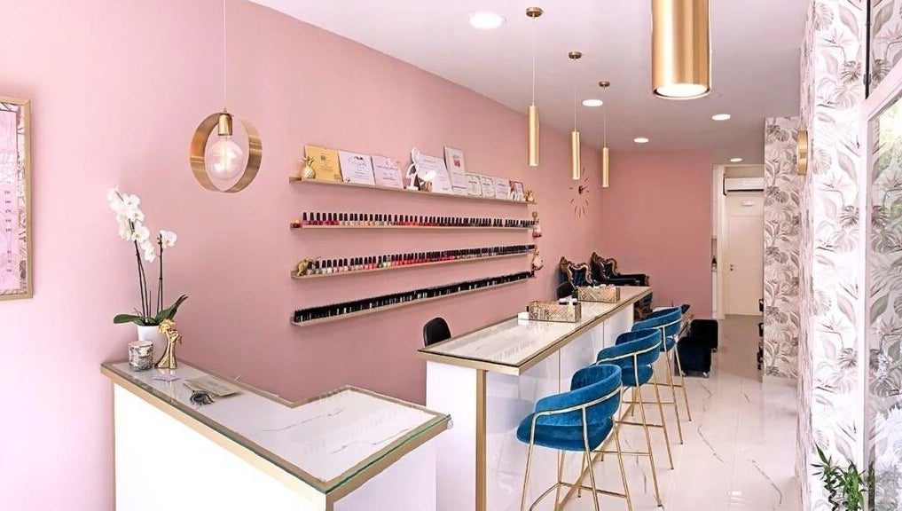 Κομψό εσωτερικό του Ονυχοκοπτείον στο Παλαιό Φάληρο, GR με ροζ τοίχους και μπλε καρέκλες.