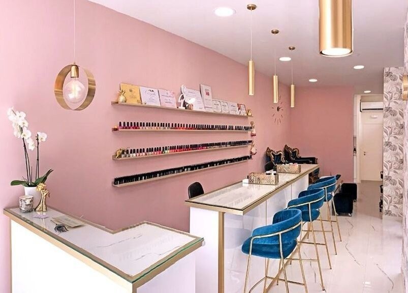 Κομψό εσωτερικό του Ονυχοκοπτείον στο Παλαιό Φάληρο, GR με ροζ τοίχους και μπλε καρέκλες.