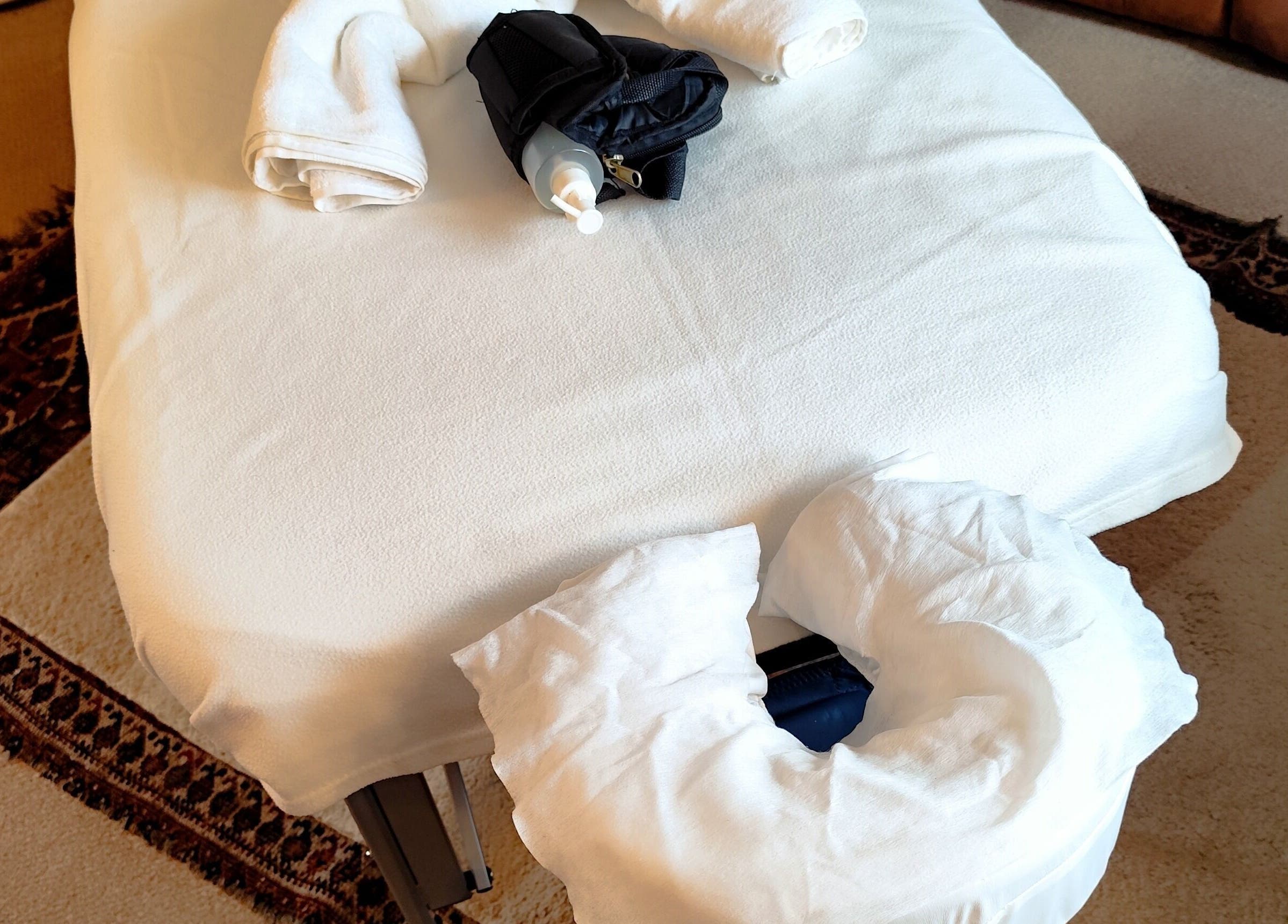 Massage table setup at MP's Mobile Massages, Ipswich, GB featuring white towels and oils.
