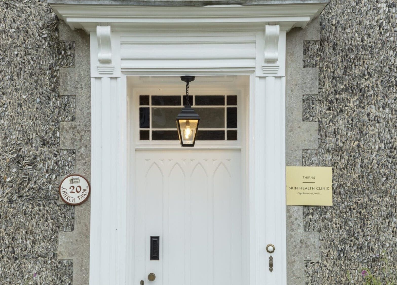 White door entrance of Thirns in Bath, England, GB, with classic lantern and stone walls.