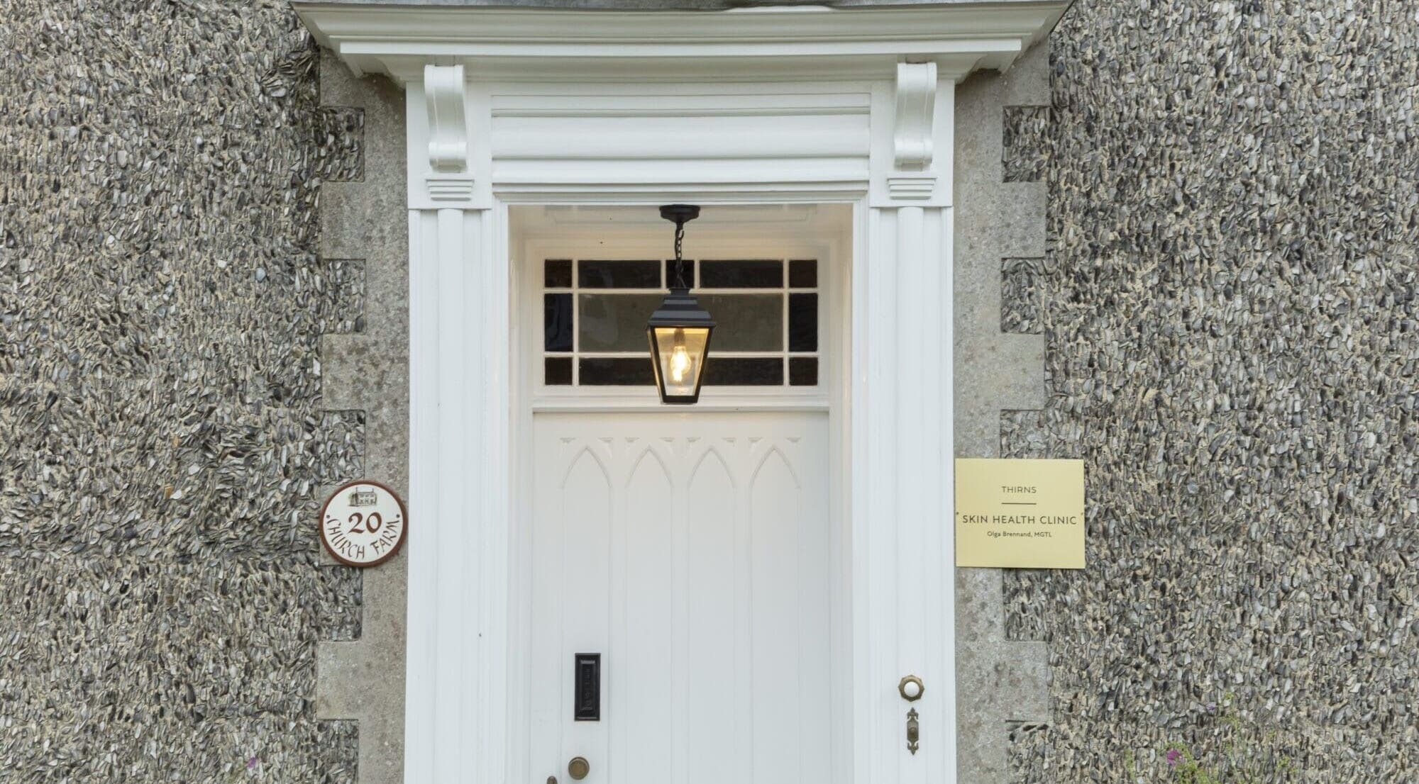 White door entrance of Thirns in Bath, England, GB, with classic lantern and stone walls.