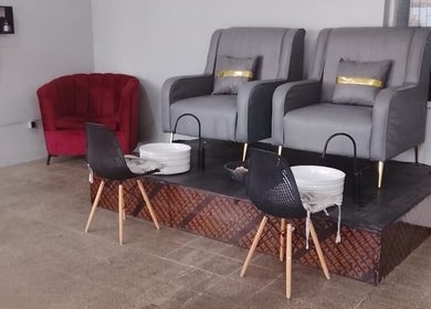 Área de pedicure elegante na Ezer Estética Lda, Matola, Maputo, MZ, com poltronas cinzas e bacias brancas.