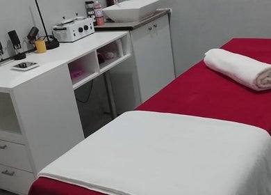 Sala de tratamento serena na Ezer Estética Lda, Matola, Maputo, MZ com mesa de massagem e toalhas brancas.