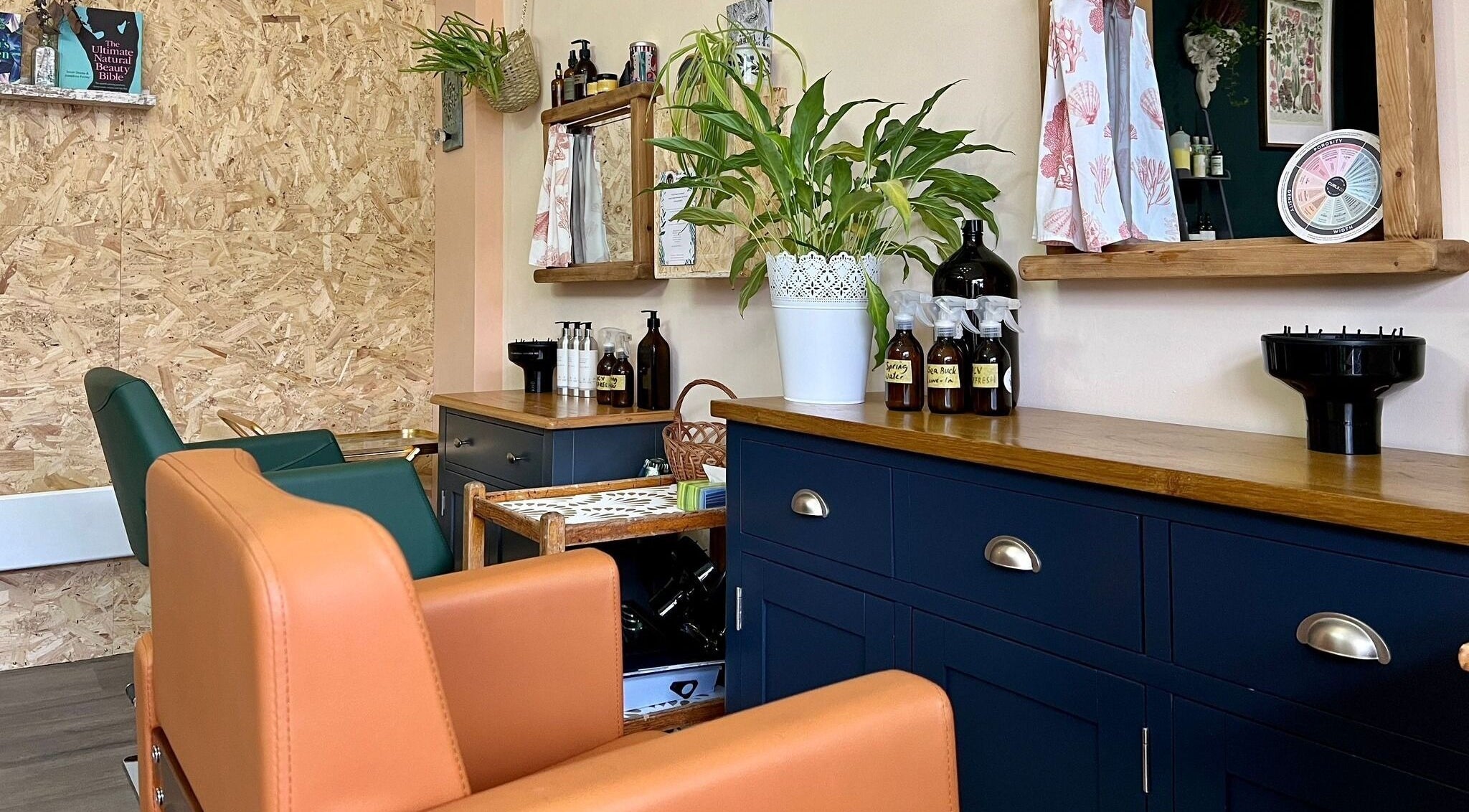Interior view of MANU Botanicals & Hair Studio in BS165LS, England, GB, featuring stylish chairs and greenery.