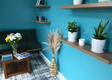 Cozy lounge at Naree Thai Massage, Auckland, NZ, with plants, teal walls, and a plush sofa.