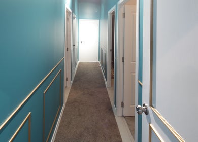 Chic hallway leading to rooms at Naree Thai Massage, Auckland, NZ, featuring vibrant blue walls and stylish decor.