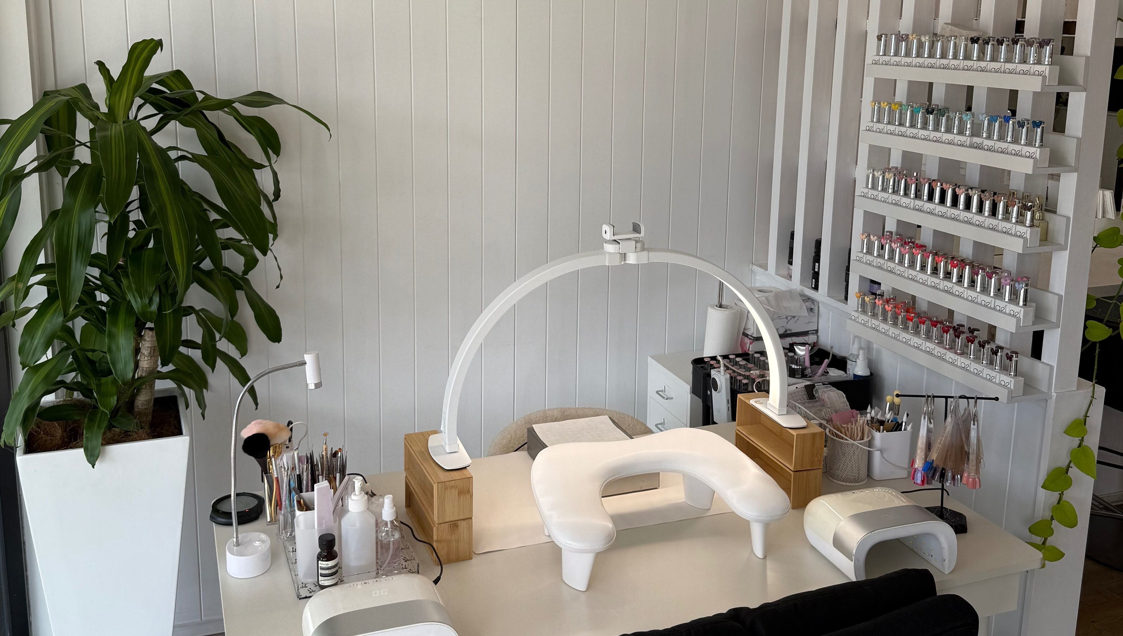 Modern nail station at EKM Nails, Main Beach, Queensland, AU, showcasing organized polish display and plant decor.