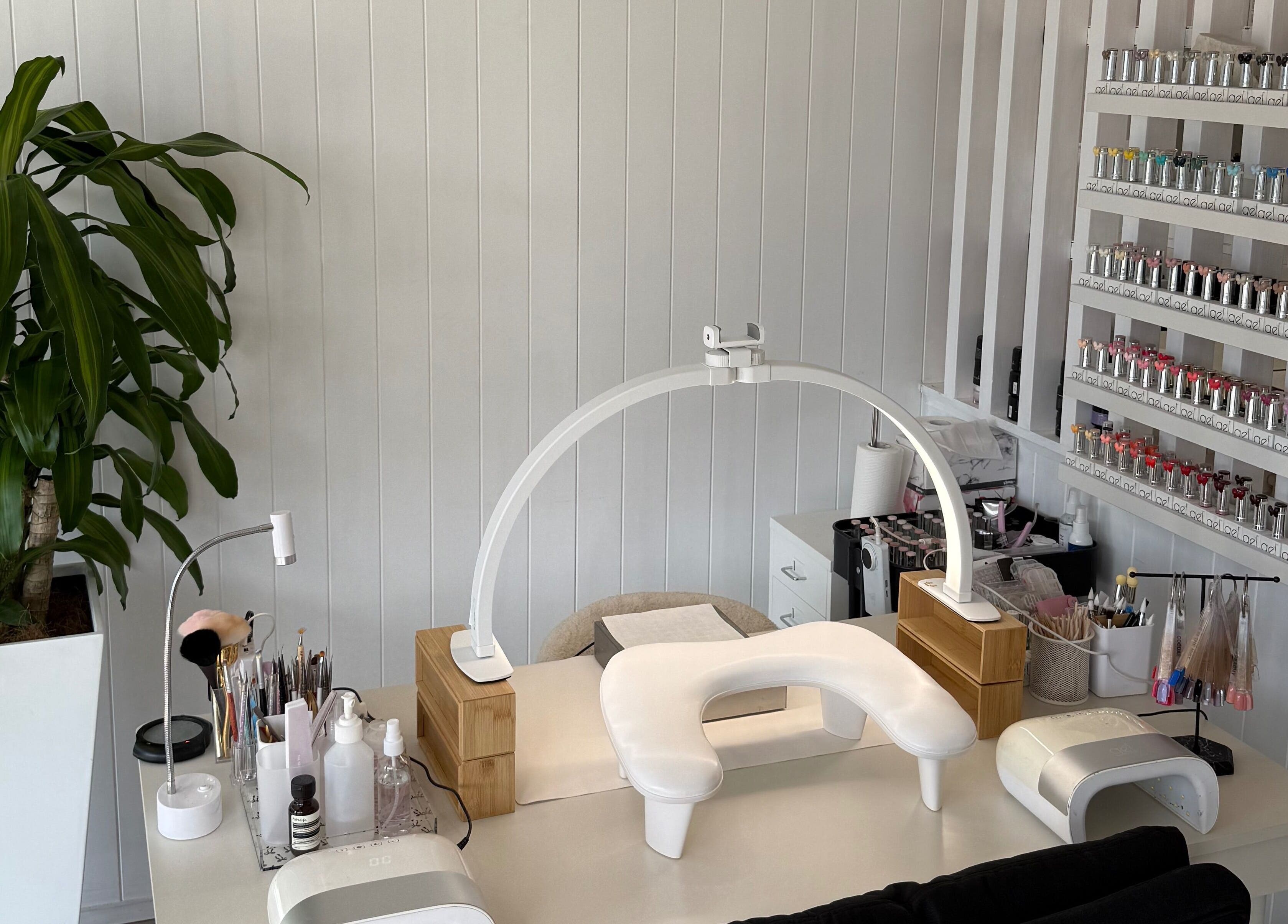 Modern nail station at EKM Nails, Main Beach, Queensland, AU, showcasing organized polish display and plant decor.
