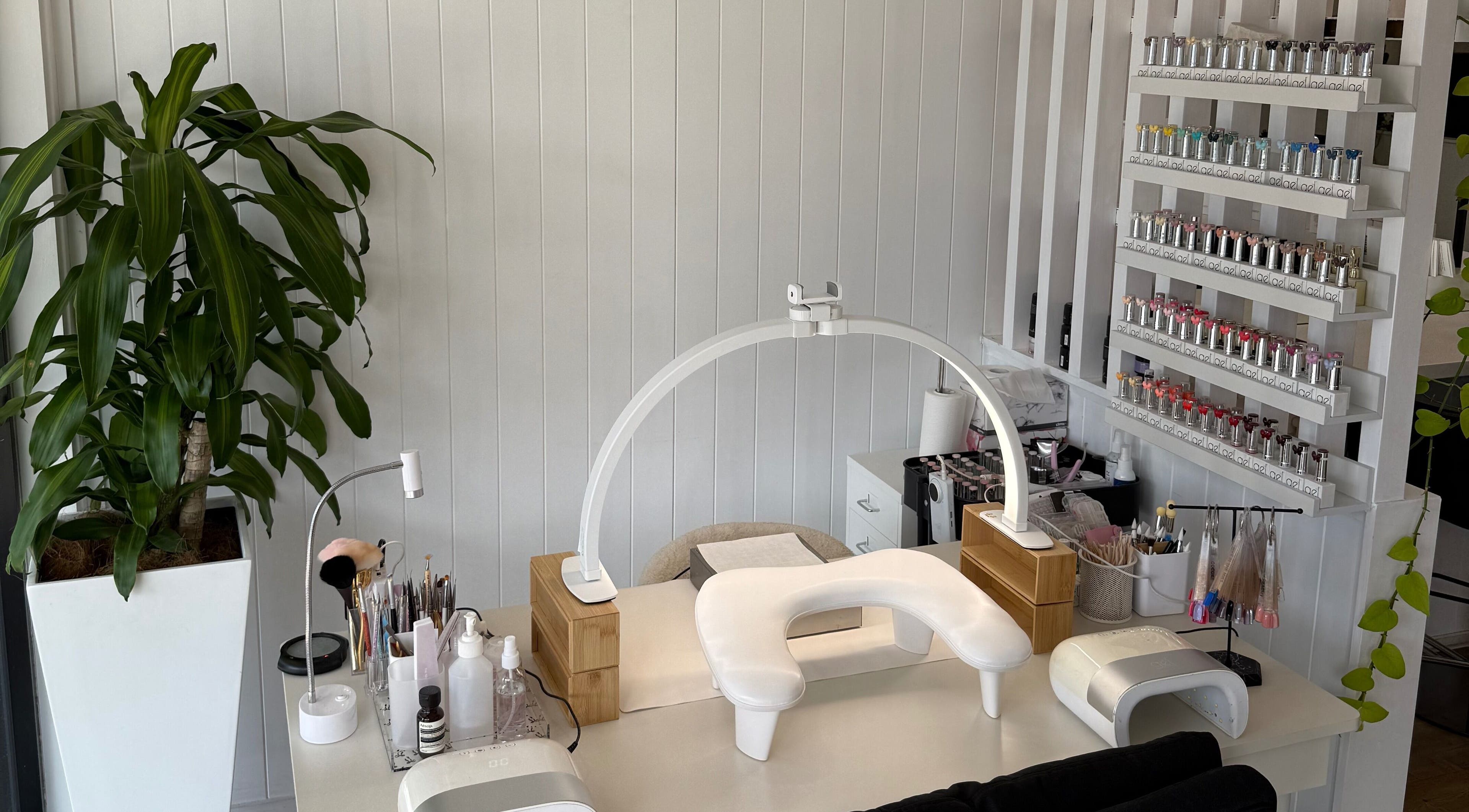 Modern nail station at EKM Nails, Main Beach, Queensland, AU, showcasing organized polish display and plant decor.