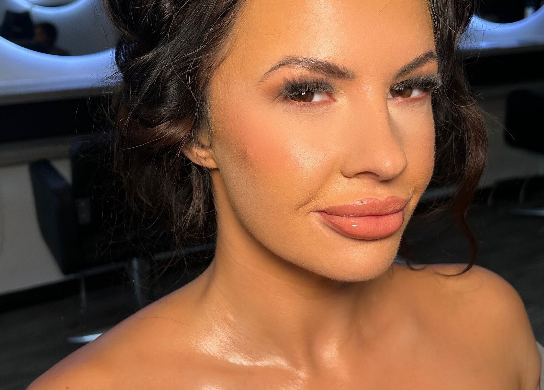 A close-up of a woman with styled hair and glowing makeup at Hannah Kathleen, Birmingham, England, GB.
